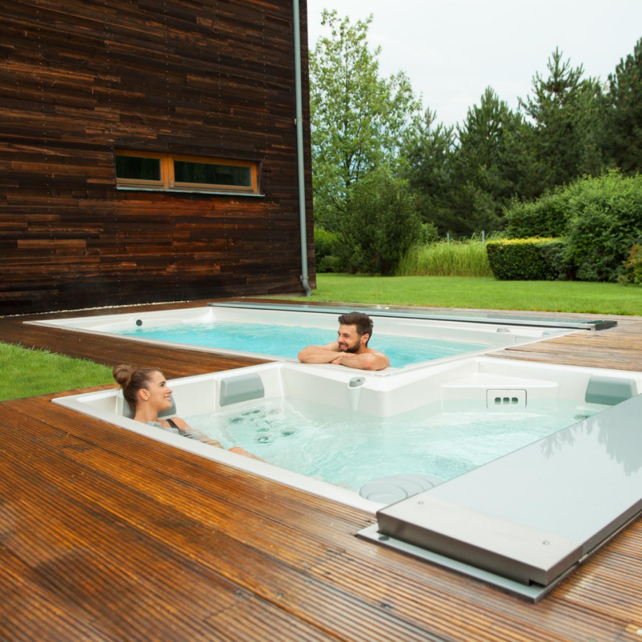 Pár relaxuje vo vonkajších kúpeľoch USSPA a bazénoch swim spa nainštalovaných na drevenej terase